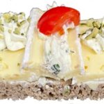 Bio-Vollkornbrötchen, belegt mit mildem Brie, Tomatenscheiben und Kürbisaufstrich.