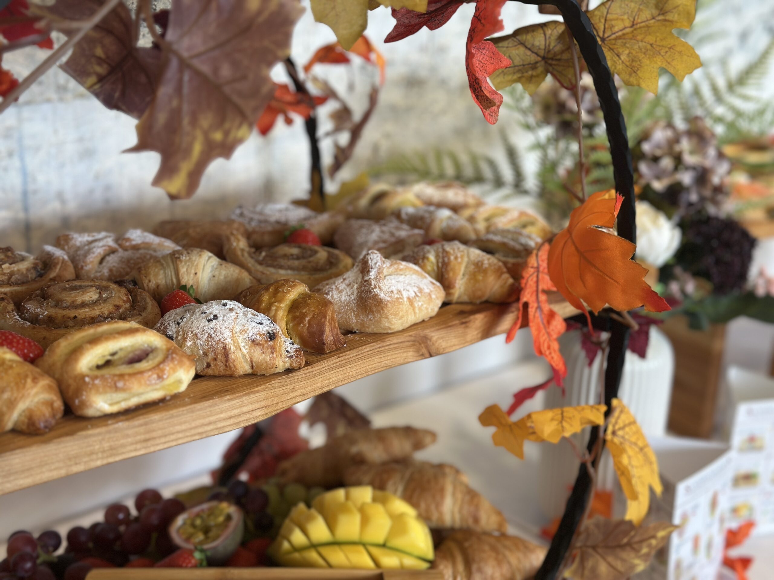 Herbstlich dekoriertes Frühstücksbuffet mit Plundergebäck, Croissants und Obstetageren.